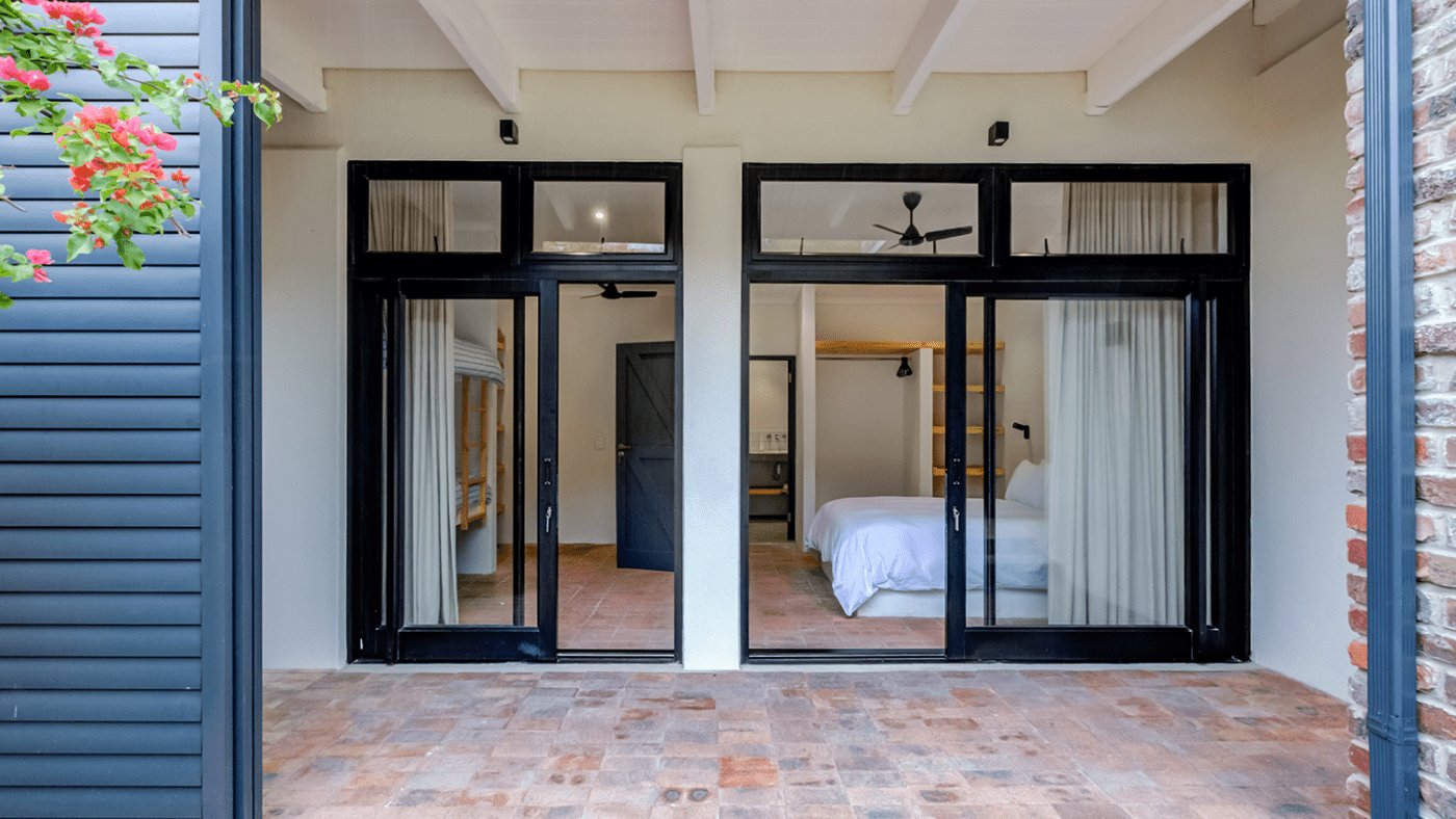 Black aluminium doors opening from a bedroom onto a brick terrace