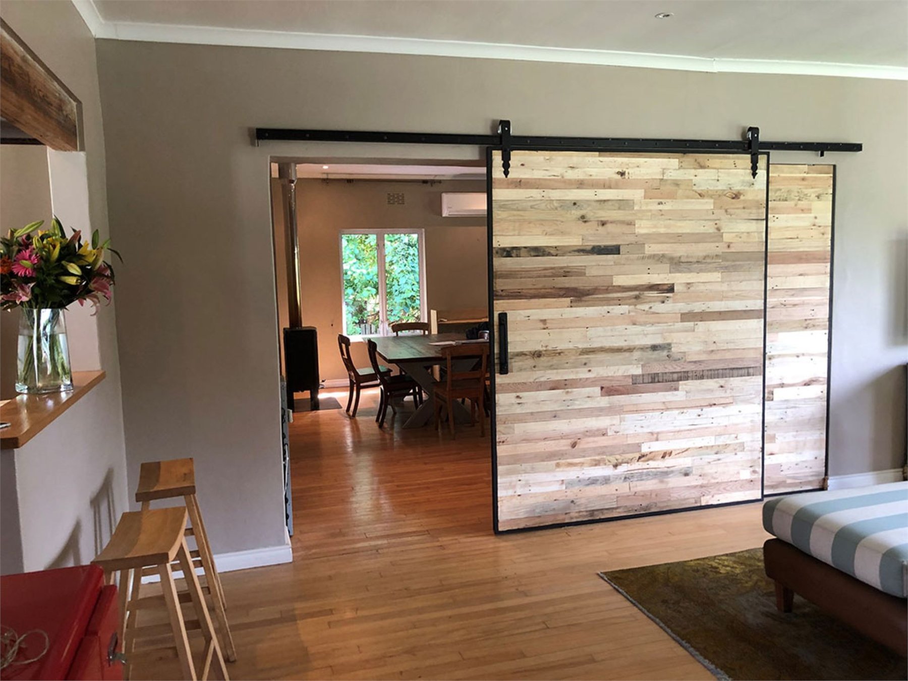 Reclaimed multi-tone timber barn door on a black steel track in a dining room