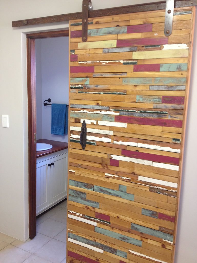 Barn door clad in mixed reclaimed timber offcuts in warm tones