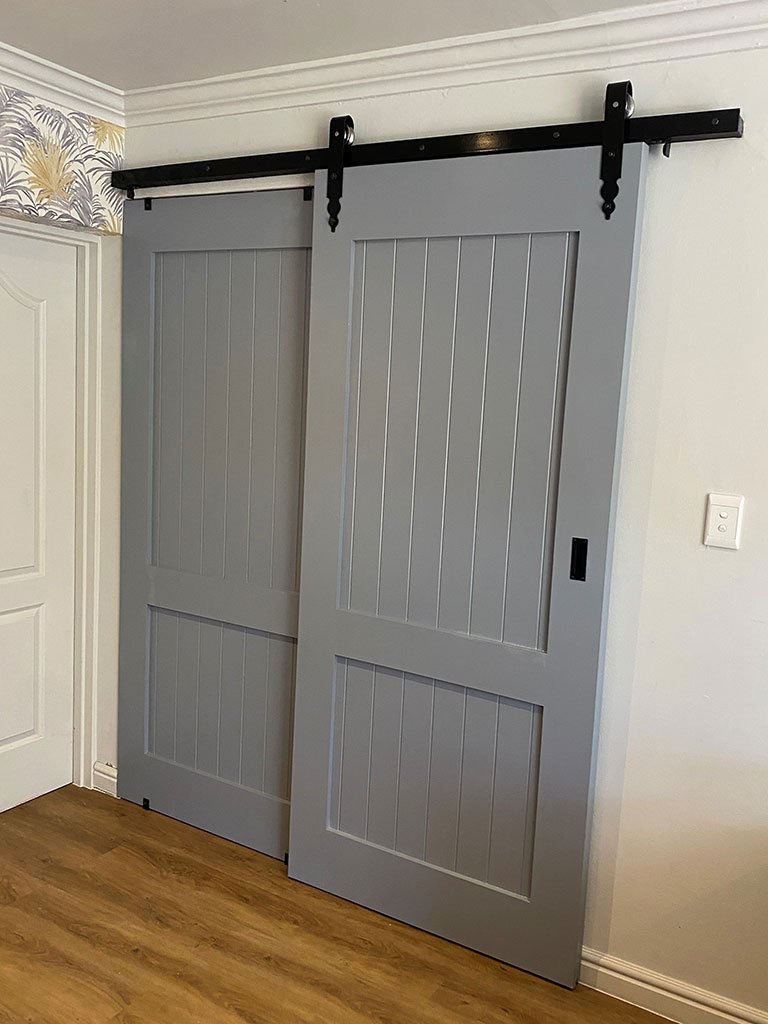Soft grey panelled barn door on a matt black track