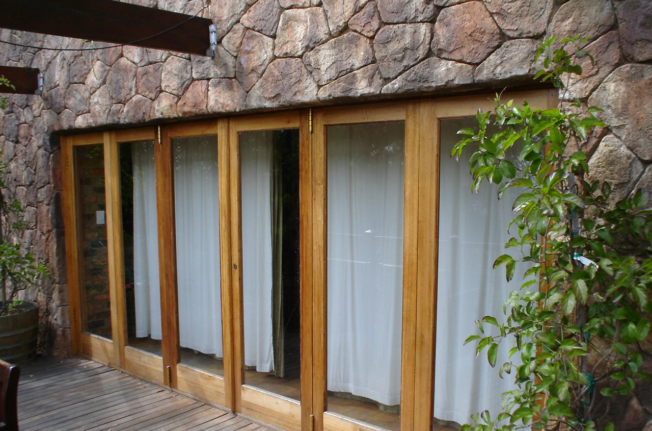 Timber folding doors set into a natural stone wall, opening onto a deck