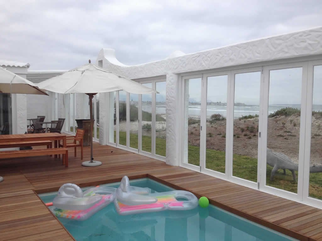 Poolside patio enclosed with white folding doors overlooking the sea
