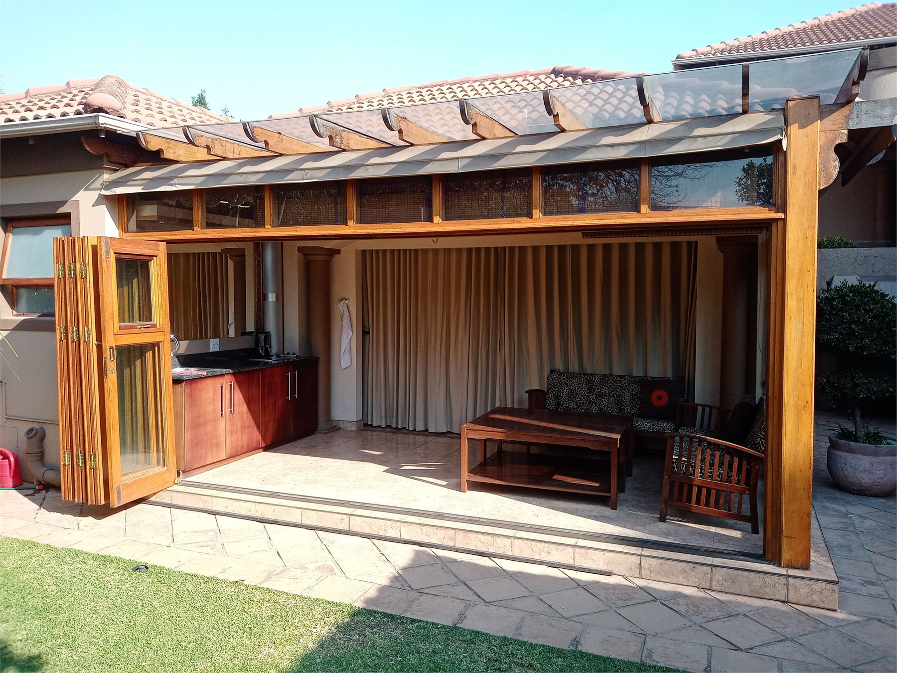 Thatched entertainment patio enclosed with hardwood folding window doors