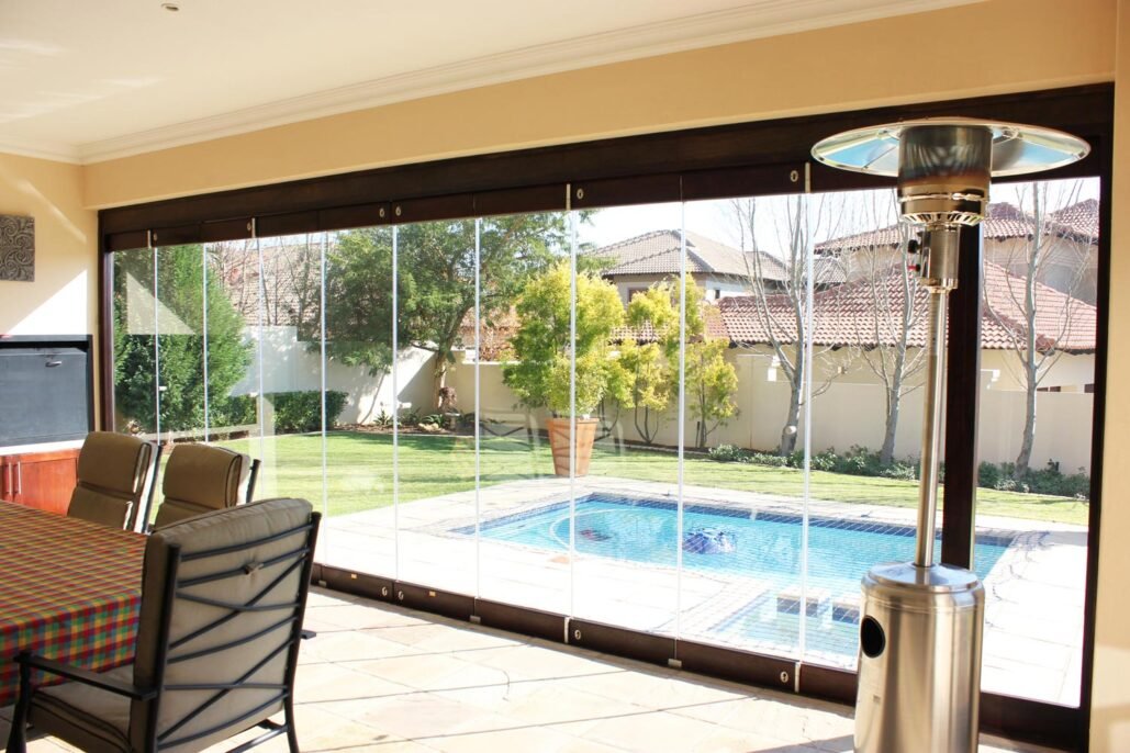 Poolside patio enclosed in frameless glass with a timber head