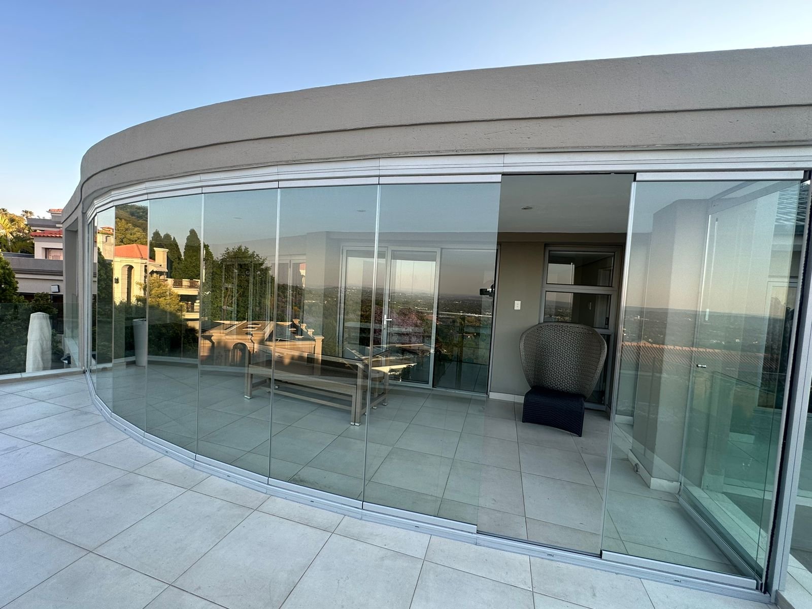 Curved frameless glass enclosure wrapping a poolside terrace